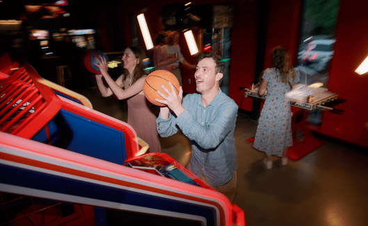 2_adults_playing_a_basketball_shooting_arcade_game