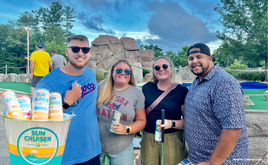 4 adults posing in front of out mini golf course - they used our free mini golf promo